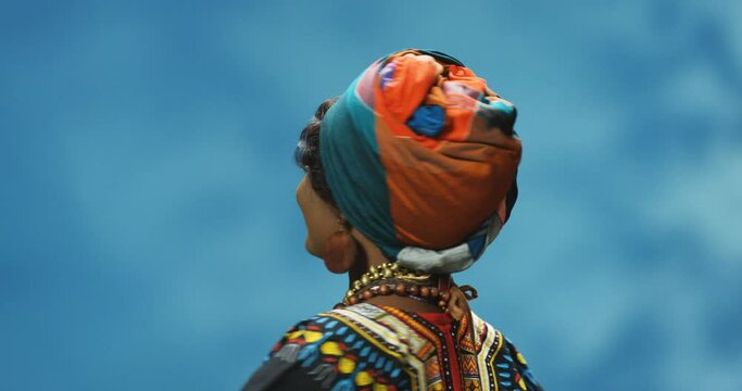Young African American beautiful woman in traditional colorful outfit dancing and spinning around with smile. Female cheerful dancer whirling round and having fun.