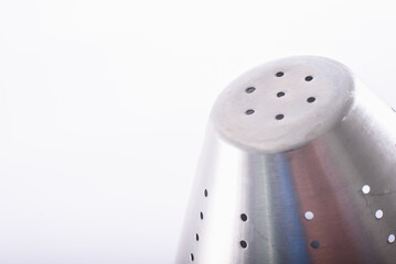 Shiny stainless steel metallic detail strainer isolated in a white minimalist kitchen.
