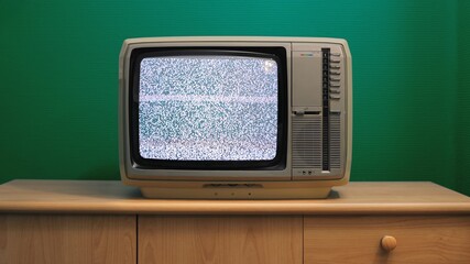 No signal just noise on old analogue TV set in front of green wall