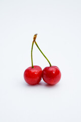 Two fresh cherries placed on a white background