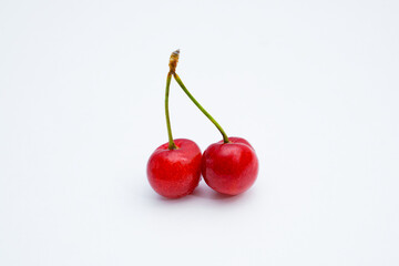 Two fresh cherries placed on a white background