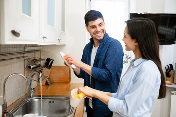 Portrait of young lovely couple washing dishes