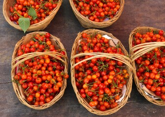 Red cherries with stem and leaves in straw baskets