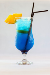 A fresh summer fruit and citrus blue coloured cocktail with a piece of orange