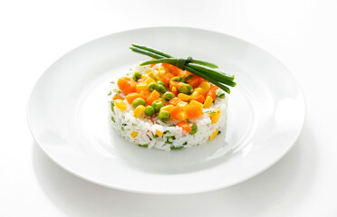 Boiled rice with vegetables, garnish in a plate on the table. Isolate
