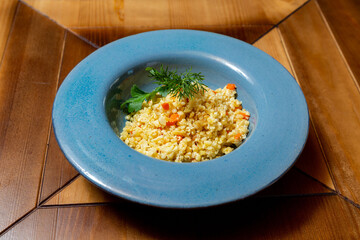 Rice porridge with herbs, side dish for meat in a plate on the table.
