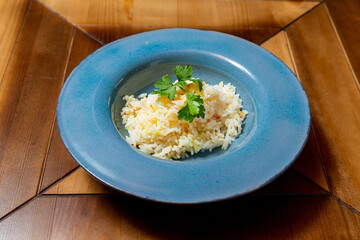 Rice porridge with herbs, side dish for meat in a plate on the table.
