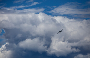 Fototapeta na wymiar Transport plane banking left and cumulus clouds