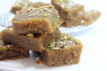 Indian Traditional sweet Lapsior shira or Halwa made from broken wheat,jaggery and desi gheeand garnished with nuts.selective focus.