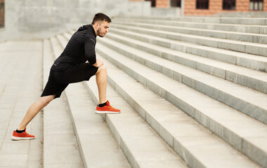 Sportsman stretching legs on gray city steps