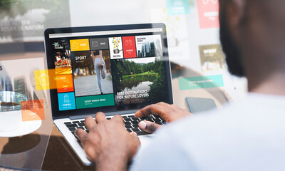 Human computer interaction. Close up of black guy making online search via laptop, collage with website design on screen