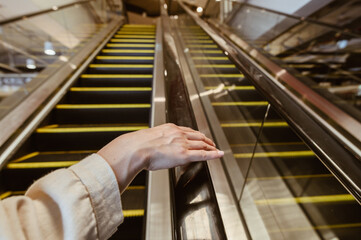 Close up of woman hand touching escalator handrail while using escalator in shopping mall for moving to another floor. Cocneptual of woman when visit shopping mall.