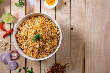 Instant noodles in bowl on wood background top view, Asian meal on a table.