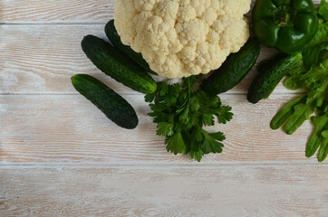 Vegetable background green healthy vegetables on a white wooden table bell pepper cauliflower and cucumbers. Super food and proper nutrition. Greens lettuce and parsley. Space for text