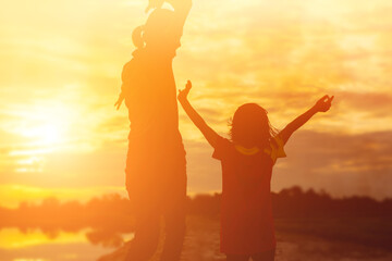 Fototapeta premium Mother encouraged her daughter out of the shadows at sunset.