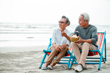 Romantic of senior couple sitting in deckchair on the beach together near sea and looking at the sea. Love is everything,.Retirement age concept and love, copy space for text