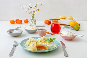 Fruit dumplings stuffed with apricots, sprinkled with cottage cheese and sugar, topped with melted butter, with creme fraiche with grated lime zest and embellished with mint. Hibiscus tea in glass.
