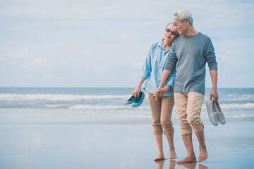 Romantic senior couple while walking and snuggle shoulder at his lover that is holding his arm at...