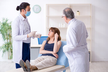 Obraz premium Two male doctors and young woman in plastic surgery concept