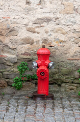 Red fire hydrant against a stone wall