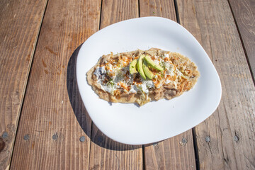 top view of huarache mexican food dish. with sauce, meat and avocado