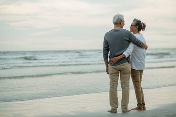 Rear view of Romantic senior couple standing together hugging each other on beach,.Retirement age...