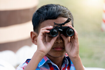 Close up little boy use binoculars. Tourism with a lawn.