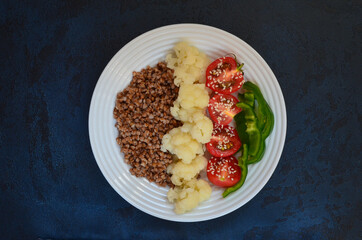 Super food buckwheat with vegetables cauliflower sweet peppers cherry tomatoes with sesame top view. Concept of healthy and vegetarian food