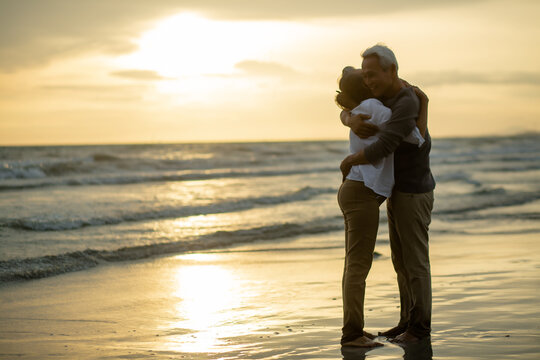 Romantic loving senior wife caress beloved husband cuddling and looking in eyes. on beach during sunset near sea,  Elderly love,.Retirement age concept and love, copy space for text
