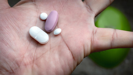 Pills in a palm hand look like human face: Painkiller pill, Antibiotics pill, Muscle Dehydration pill, Swelling pill and Calcium tablet in the palm for spine subsidence