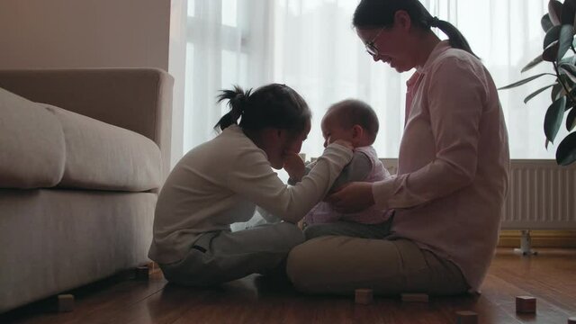 Slow motion of asian woman sitting with her two daughters playing together at home little Chinese girl having fun with her baby sister and parent family lifestyles with kids