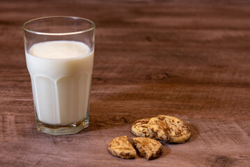 Leche en vaso de vidrio transparente con galletas de chocolate y vainilla sobre madera 