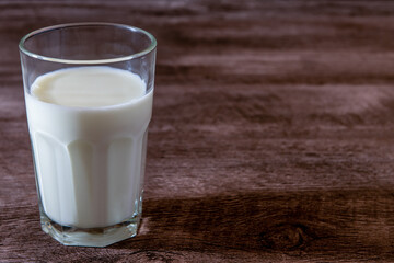 Leche en vaso de vidrio transparente sobre base de madera 