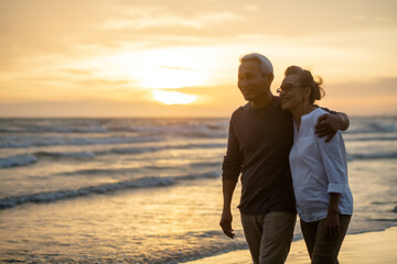 Romantic of senior man smiling while hugging his wife and walking the beach during sunset, image not focus..Retirement age concept and love, copy space for text