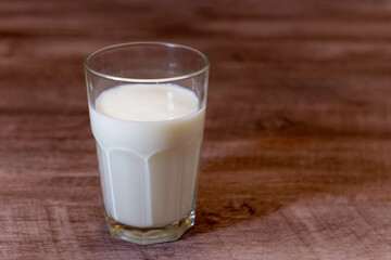 Leche en vaso de vidrio transparente sobre base de madera.