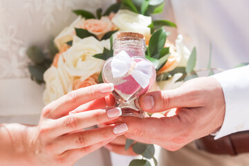 Bride and groom pouring colorful different colored sands into the crystal vase close up during symbolic nautical decor destination wedding marriage unity ceremony on sandy beach in front of the ocean 