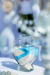 Bride and groom pouring colorful different colored sands into the crystal vase close up during symbolic nautical decor destination wedding marriage unity ceremony on sandy beach in front of the ocean 