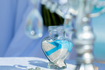Bride and groom pouring colorful different colored sands into the crystal vase close up during symbolic nautical decor destination wedding marriage unity ceremony on sandy beach in front of the ocean 