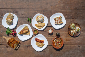 top view of variety of mexican food like tacos, enchiladas, pozole, birria, tamal, salsa, sopes