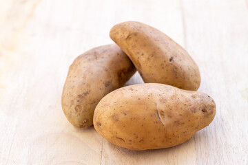 Three potatoes placed on a wooden background