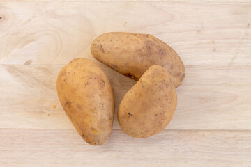 Three potatoes placed on a wooden background