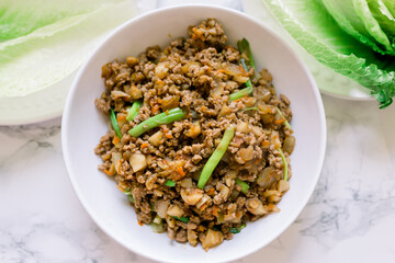 A Head of Green Lettuce and a White Bowl with Ground Chicken with Water Chestnuts for Lettuce Wraps. Asian Cooking. 