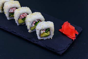Uramaki sushi rolls with surimi on a black slate