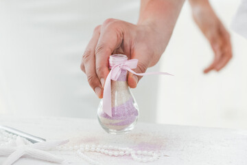 Bride and groom pouring colorful different colored sands into the crystal vase close up during symbolic nautical decor destination wedding marriage unity ceremony on sandy beach in front of the ocean 