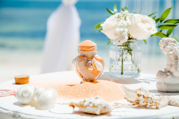 Obraz na płótnie Canvas Bride and groom pouring colorful different colored sands into the crystal vase close up during symbolic nautical decor destination wedding marriage unity ceremony on sandy beach in front of the ocean 