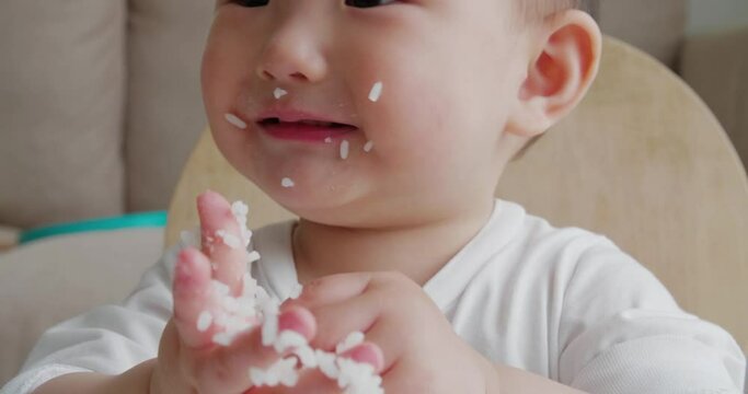 Close up of lovely baby girl eating rice by herself at home Adorable happy Asian baby eating indoor 
