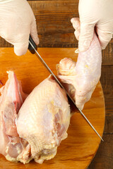 Woman cuts chicken carcass with a knife on a wooden board. © finist_4