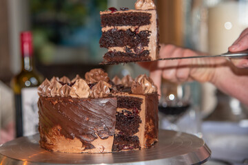 Cutting a stunningly decorated birthday wedding cake with layers inside. Chocolate fudge cake. 