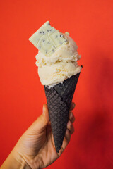 Woman hand holding a cone ice cream with white chocolate on a red background