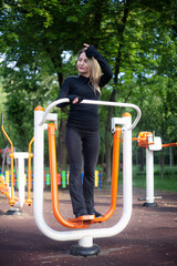 Fototapeta premium The girl on the summer sports ground does sports exercises on the stepper. Healthy lifestyle.